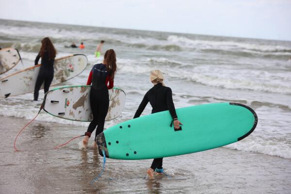 Surfen als actieve teambuilding tijdens een bedrijfsuitje op het strand.