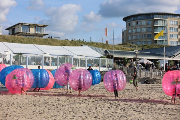 Spelers stuiteren in grote opblaasballen over het zand terwijl ze fanatiek scoren.