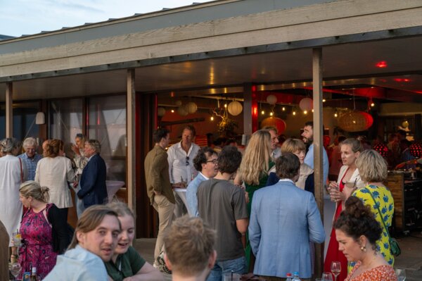 Buitenborrel op het zonnige terras van Tijn Akersloot, met uitzicht op zee.